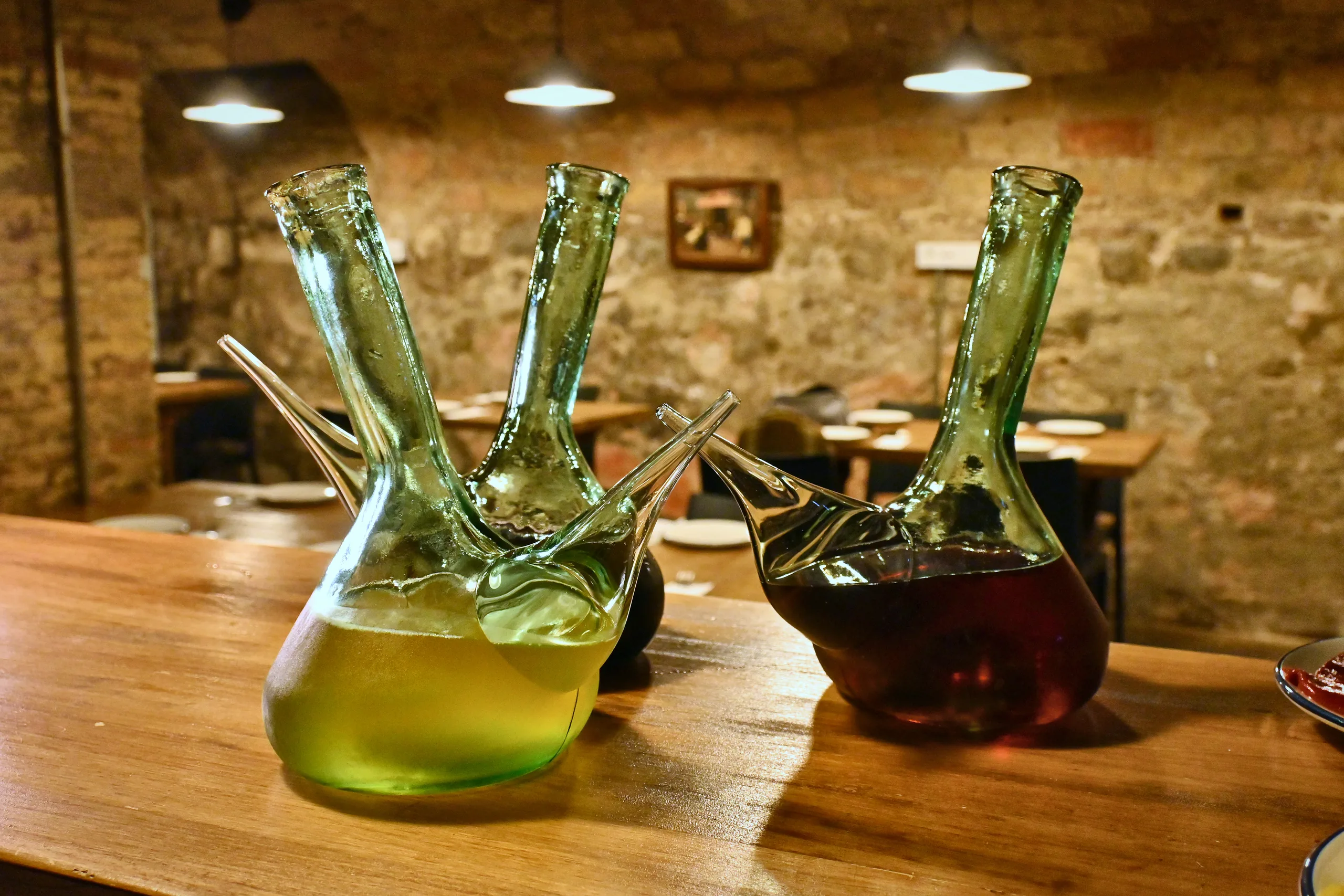 Porrones de sidra sobre la barra, con el comedor al fondo